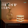 Mini mid century friendship lamp in white with black hardware glowing softly on a bedside table