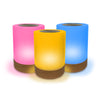 Set of three colorful cylindrical Lumi Friendship Lamps with wooden bases on a white background