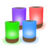Set of four cylindrical colored Lumi Friendship Lamps with wooden bases on a white background