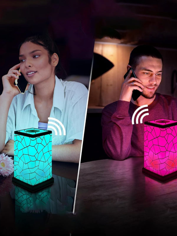 Two people using wireless phone calls with colorful lamp devices on a table.